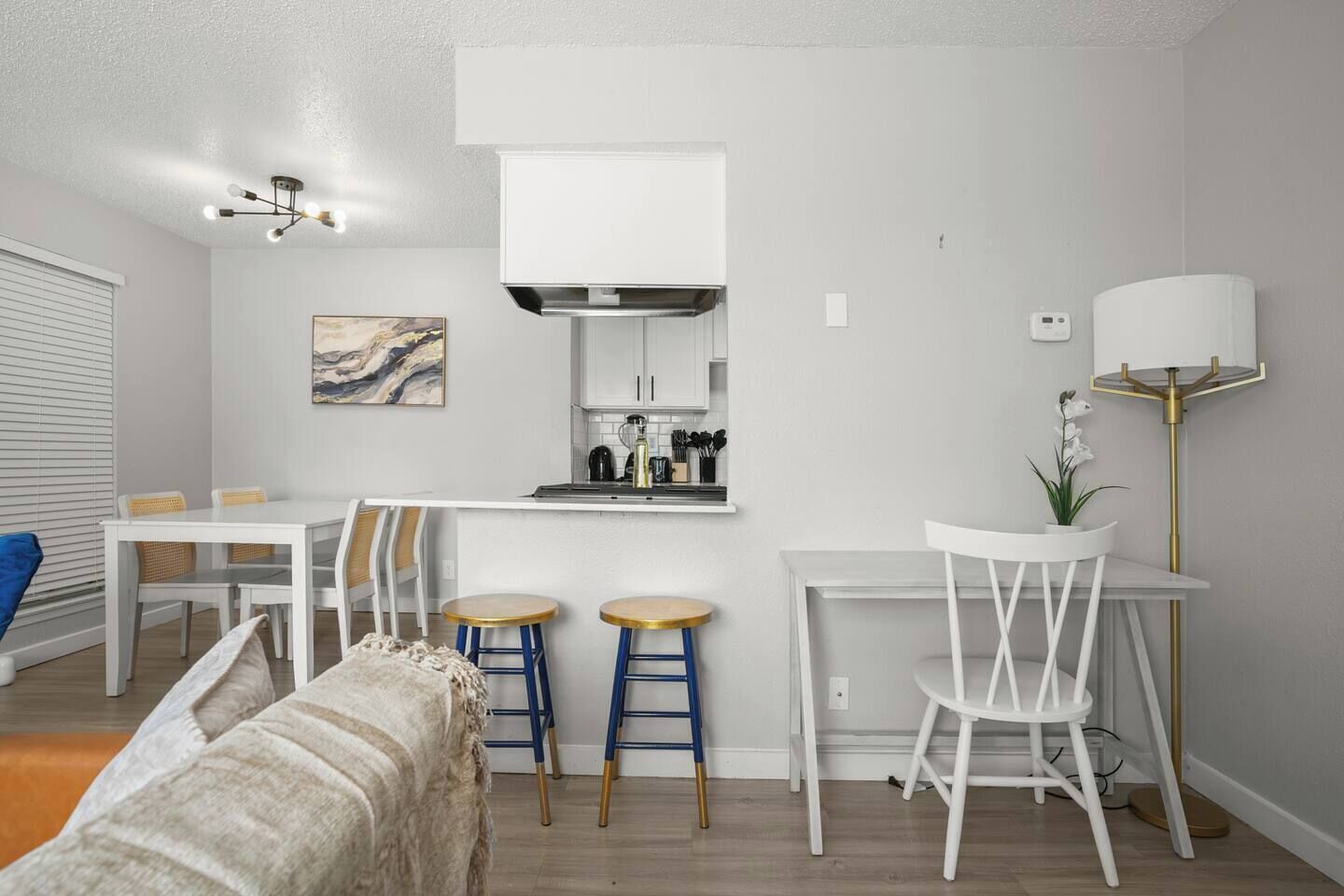 Cocina moderna con armarios blancos, una isla central y taburetes de bar.
