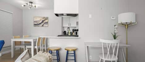 Cocina moderna con armarios blancos, una isla central y taburetes de bar.