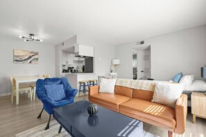 A modern living room with a sofa, a coffee table, and a dining area with a table and chairs. - Central Austin • Parking • Sleeps 5 • Pet Friendly (Austin)