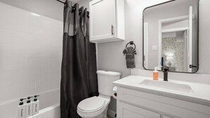 Ein Badezimmer mit Badewanne, Toilette und Waschbecken mit Spiegel.