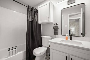 Ein Badezimmer mit Badewanne, Toilette und Waschbecken mit Spiegel.