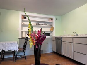 A kitchen with a dining table and chairs, a vase with flowers, and a microwave. - Charming Cozy 1-bedroom furnished apartment on 12 peaceful acres in Dorset . (Dorset)