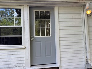 A gray front door with a window above it, a mailbox, and a light fixture on the right side. - Charming Cozy 1-bedroom furnished apartment on 12 peaceful acres in Dorset . (Dorset)