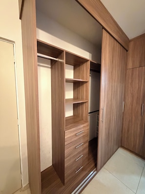 Un dressing avec des étagères en bois, des tiroirs et une tringle pour suspendre les vêtements.