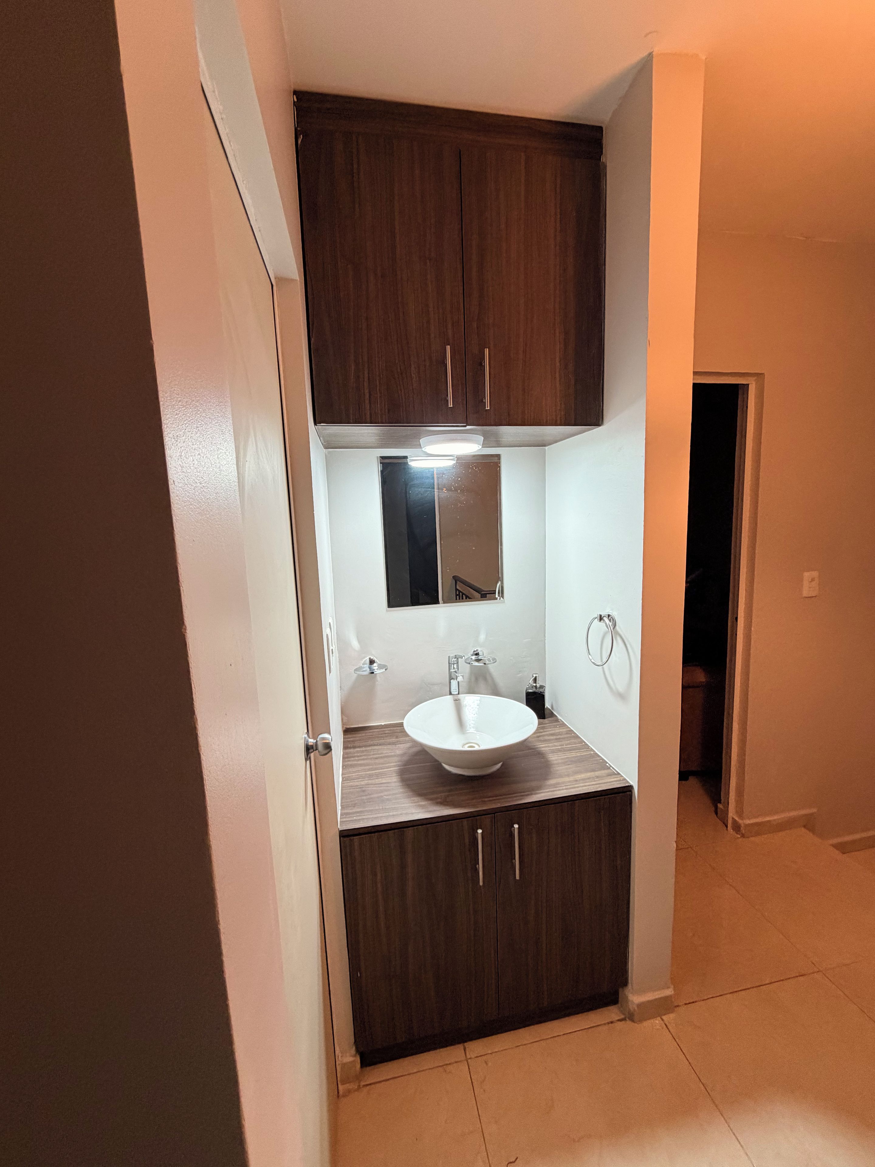 Une salle de bain avec un lavabo blanc, des meubles en bois foncé et un miroir au-dessus du lavabo.