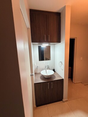 Une salle de bain avec un lavabo blanc, des meubles en bois foncé et un miroir au-dessus du lavabo.