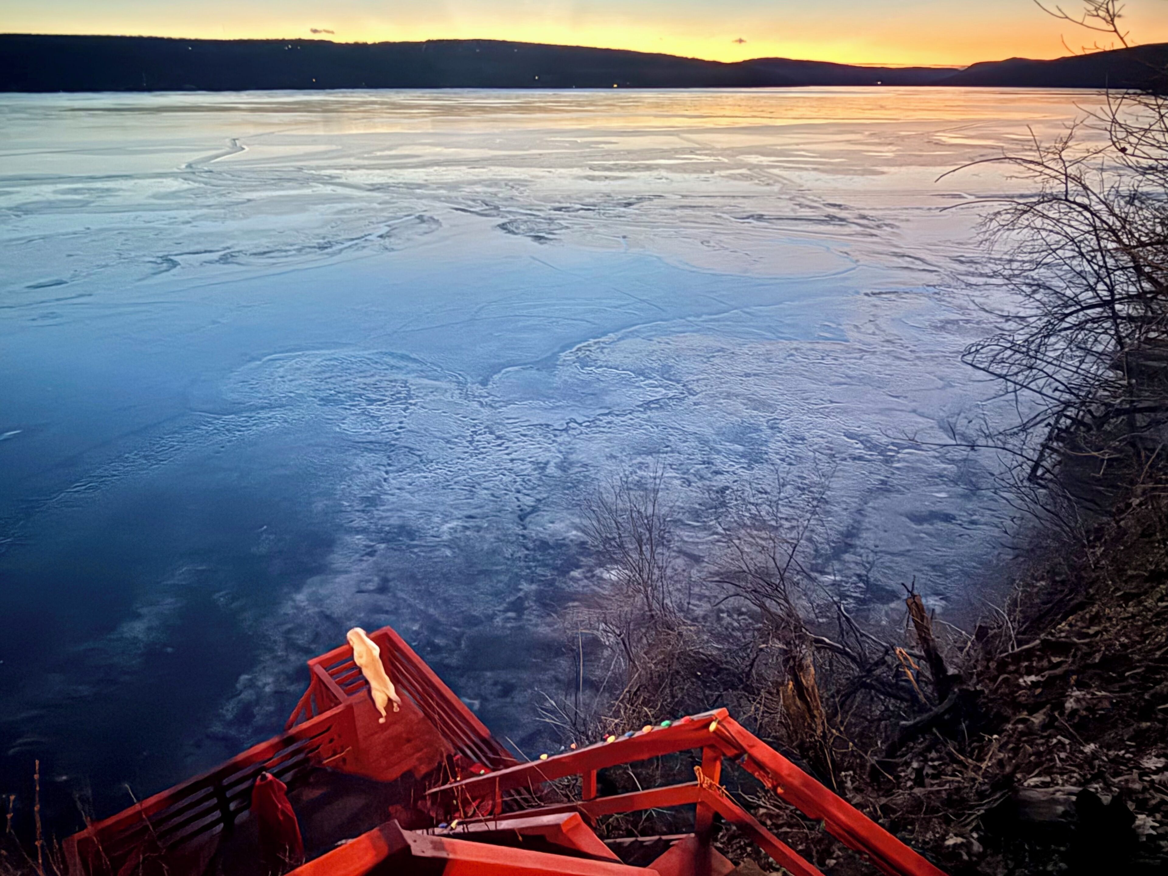A frozen lake with a red staircase leading down to the water.