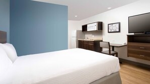 Una habitación de hotel con cama, escritorio, silla, televisor y microondas.
