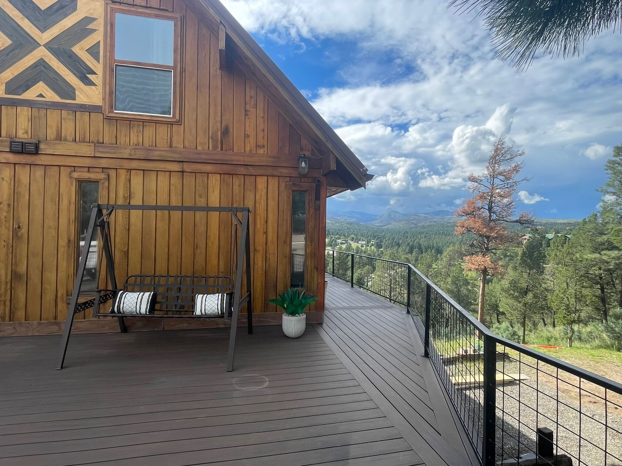 A wooden cabin with a deck, a bench, and a potted plant.