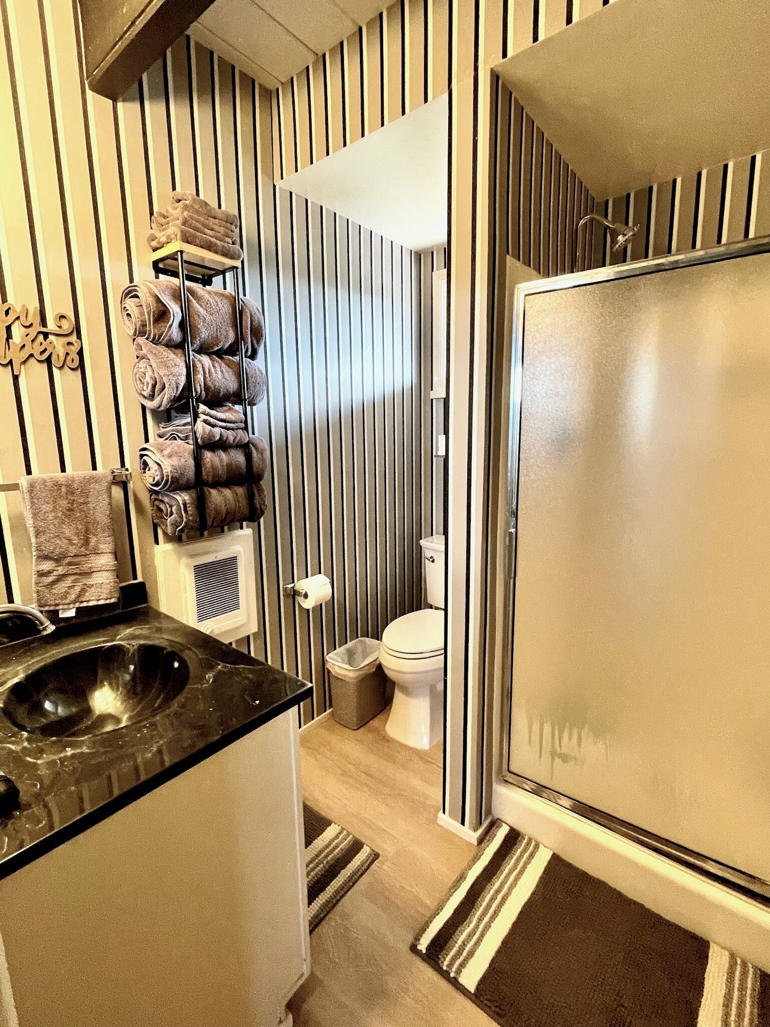 A bathroom with a black sink, a toilet, and a towel rack with towels.