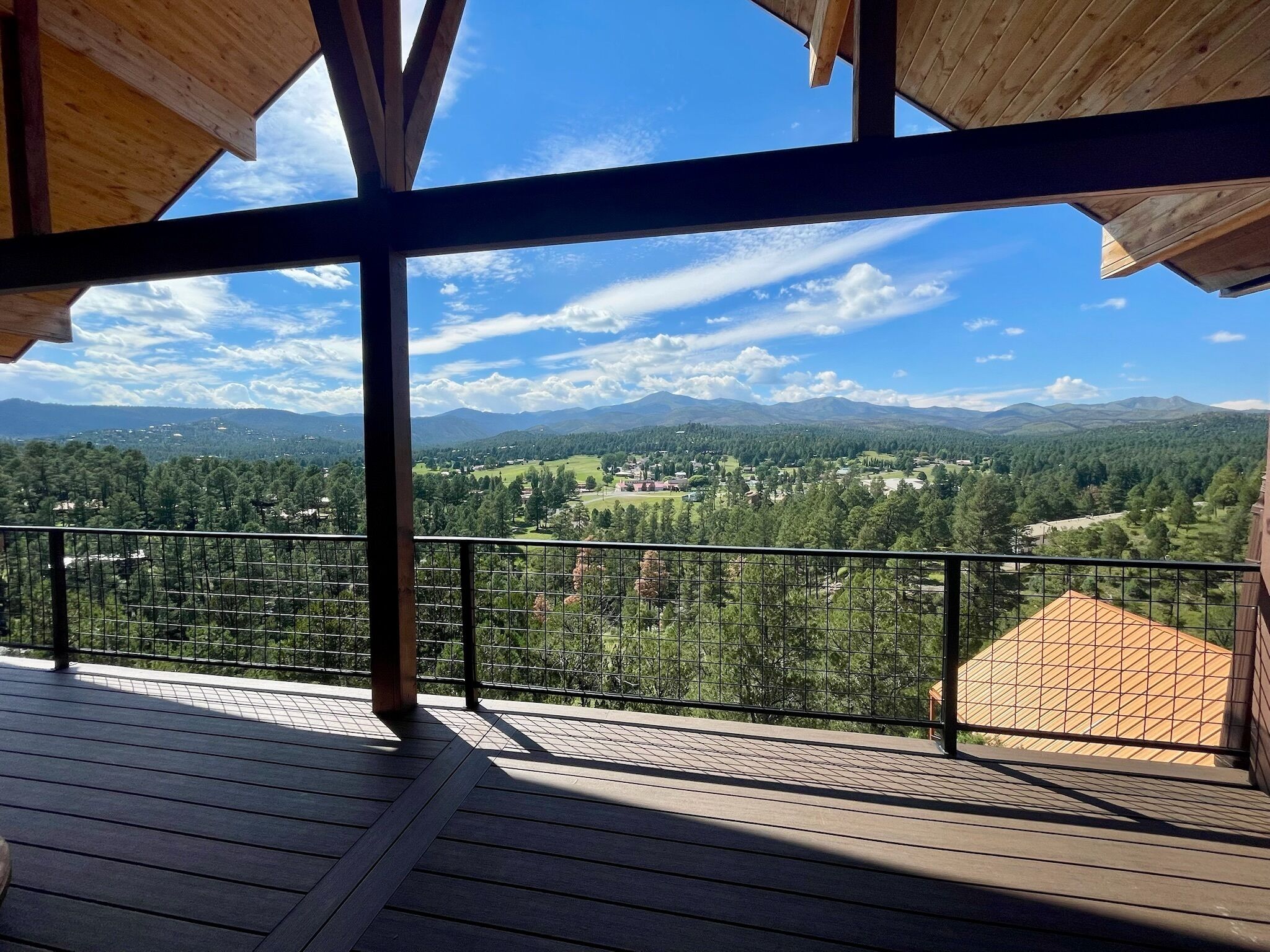 A wooden deck with a metal railing overlooking a mountainous landscape.