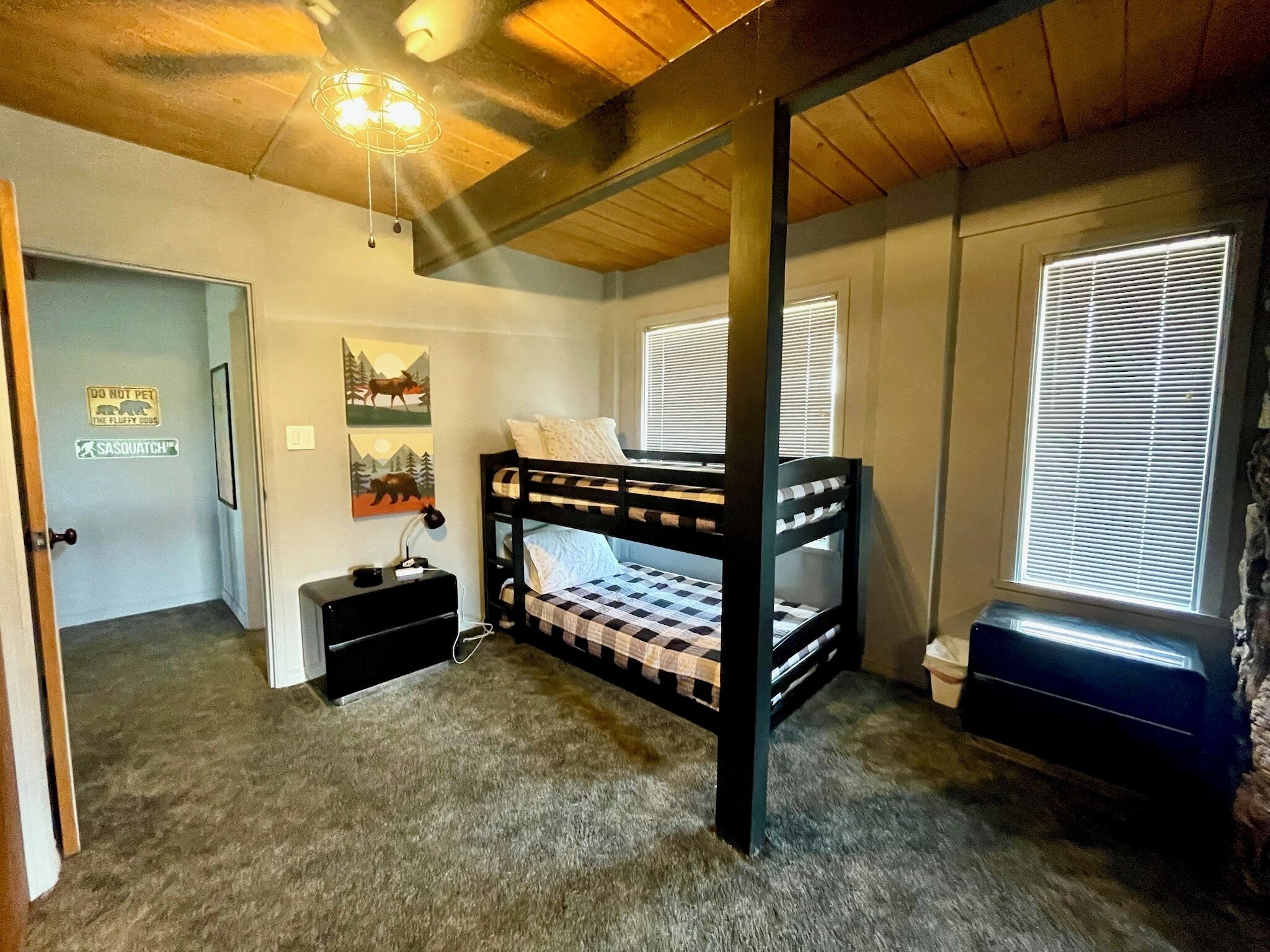 Une chambre avec un lit superposé, un bureau, une chaise, un radiateur et une porte sur laquelle est affiché un panneau indiquant « NE PAS TOUCHER ».