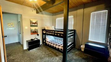 A bedroom with a bunk bed, a desk, a chair, a heater, and a door with a 'DO NOT PET' sign.