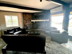 Ein modernes Wohnzimmer mit Kamin aus Stein, Ledersofas und einem großen Fenster.