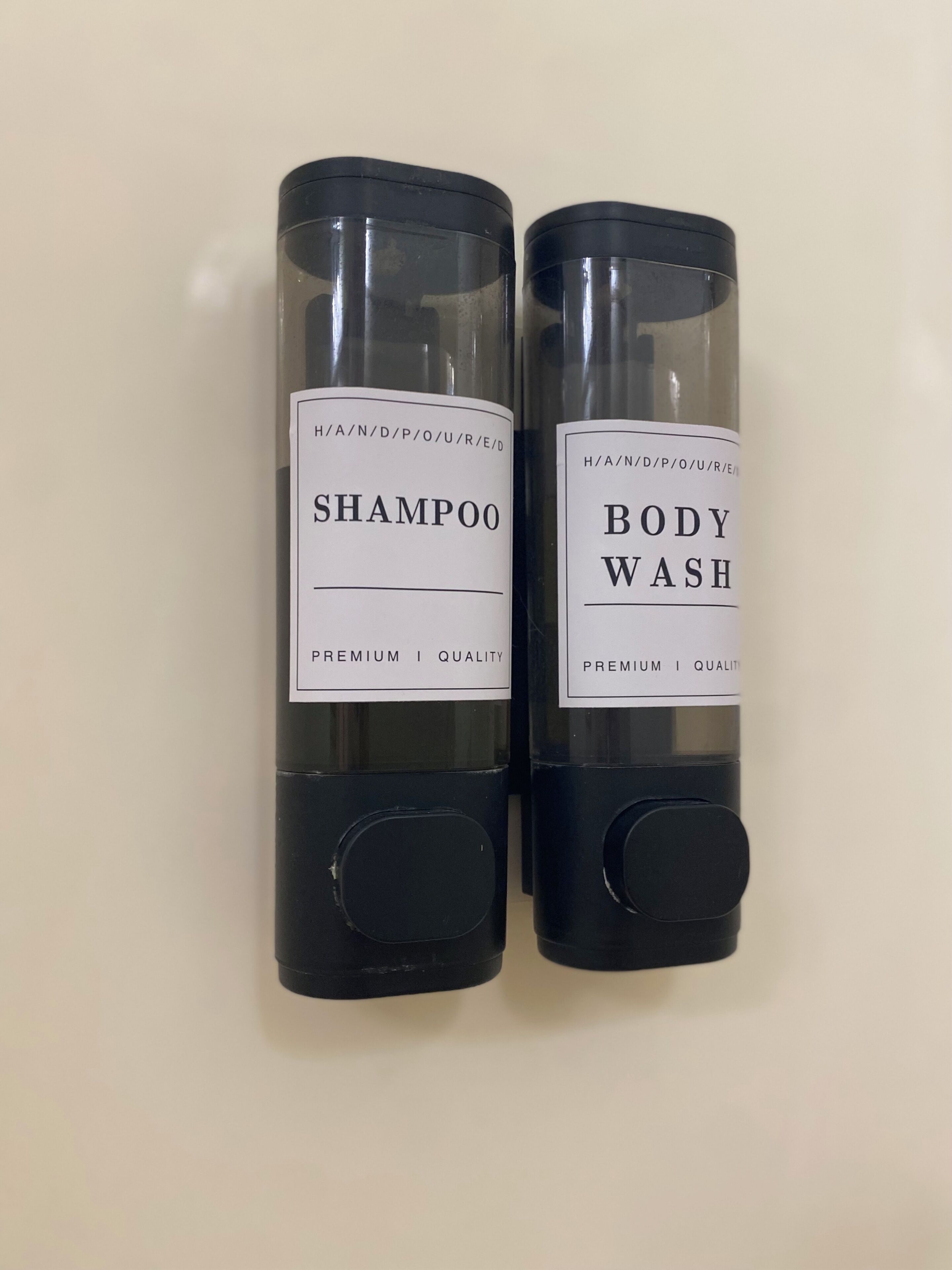 Two cylindrical containers with labels, one labeled 'SHAMPOO' and the other 'BODY WASH,' both with 'PREMIUM QUALITY' text.