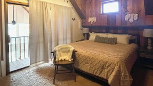 Um quarto com uma cama, uma cadeira, uma janela e uma porta.