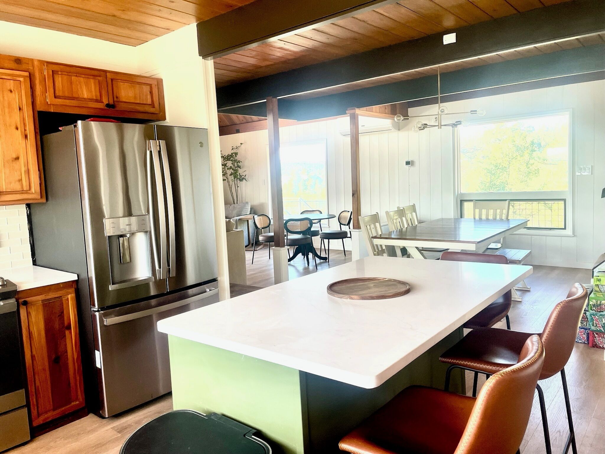 A modern kitchen with stainless steel appliances, a central island, and a dining area with chairs and a table.