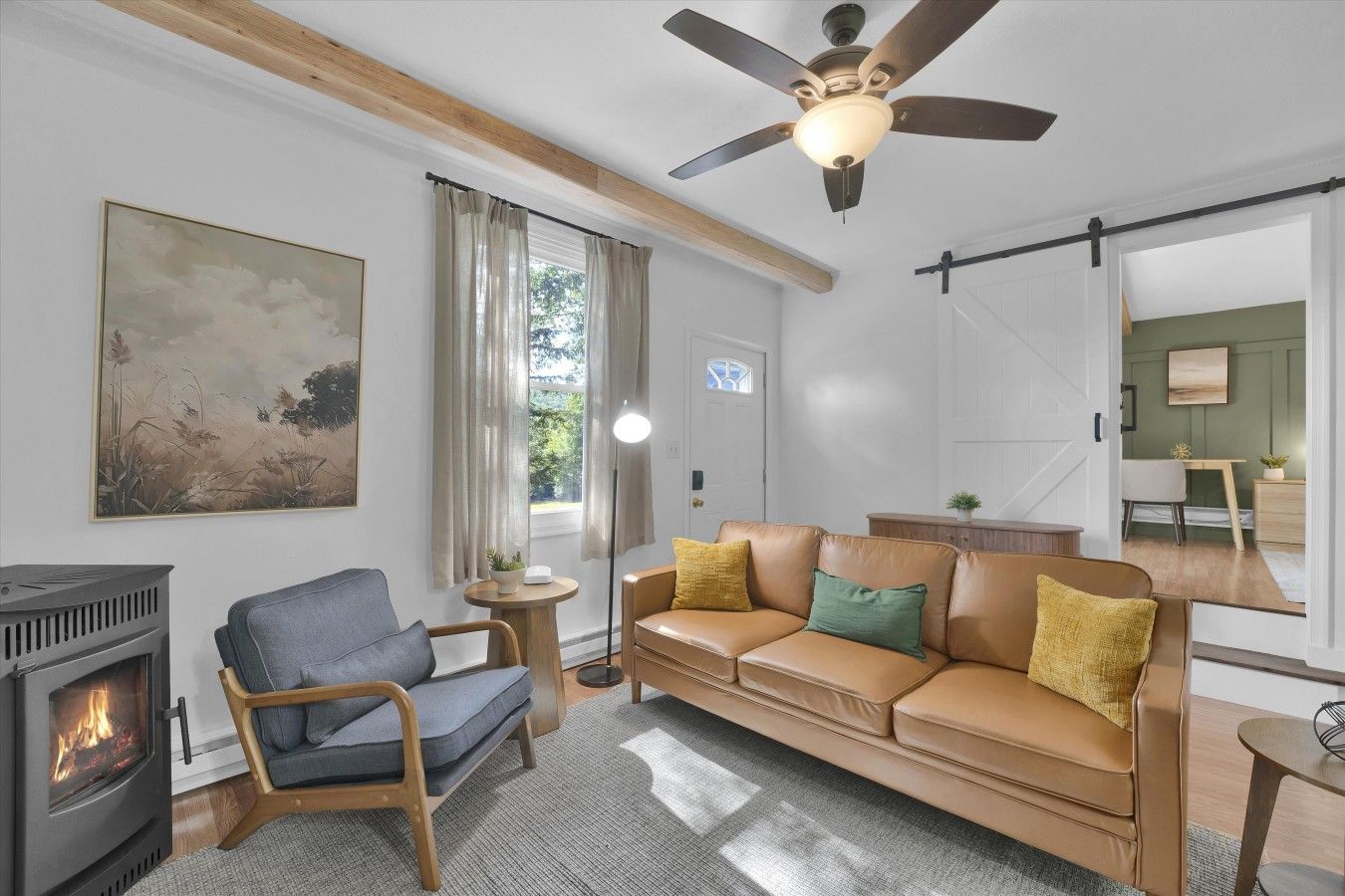 Un salon comprenant un canapé, un fauteuil, une cheminée et un ventilateur de plafond.