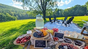 An outdoor picnic setup with a variety of food items and a sign that reads 'We hope you enjoy!'