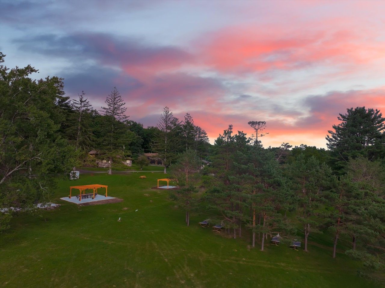 A grassy area with a gazebo, trees, and a house in the background.