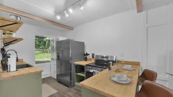A modern kitchen with a built-in refrigerator, a stove, and a dining area with a wooden table and chairs.