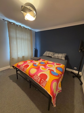 A bedroom with a bed, a ceiling light, a heater, and a window with curtains. - Room-bright Double Size Private Room in (Wellingborough)