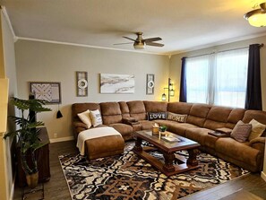 A living room with a sectional sofa, a coffee table, a floor lamp, and a ceiling fan. - Summit Retreat - Furnished Townhome, 2-Car Garage, Colorado Springs (Colorado Springs)