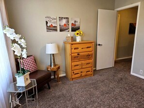 Ett rum med en byrå i trä, en lampa, en bänk och en vägg med tre tavlor.