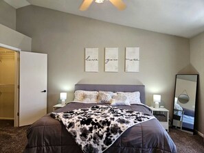 A bedroom with a bed, bedside lamps, a mirror, and a wall with three framed pieces of art. - Summit Retreat - Furnished Townhome, 2-Car Garage, Colorado Springs (Colorado Springs)