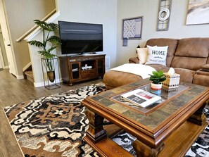 A living room with a television, sofa, coffee table, and a patterned rug. - Summit Retreat - Furnished Townhome, 2-Car Garage, Colorado Springs (Colorado Springs)