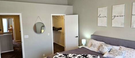 A bedroom with a bed, a ceiling fan, a walk-in closet, and a mirror.
