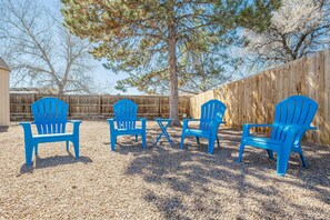 An outdoor seating area with four blue chairs and a small table, surrounded by a wooden fence and trees. - Pedal Paradise II Cozy w/fenced yard (Fruita)