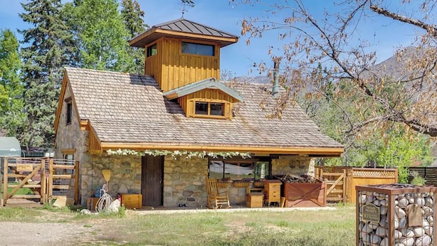A rustic cabin with a stone facade, a wooden upper level, and a covered porch area. - Charming 4-bed cottage with hot tub (Sandy)