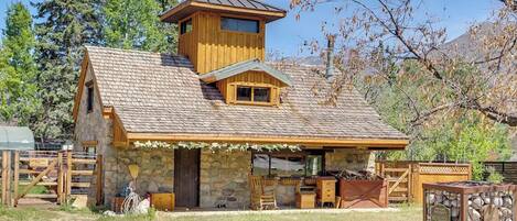 A rustic cabin with a stone facade, a wooden upper level, and a covered porch area.