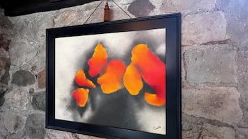 A framed abstract painting with a black frame hanging on a stone wall.