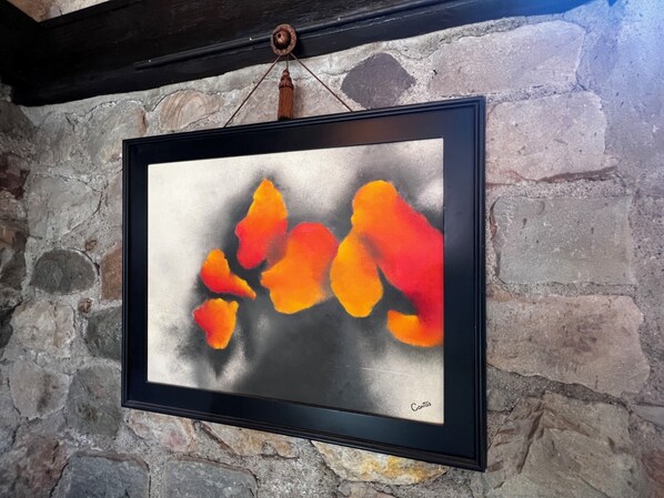 A framed abstract painting with a black frame hanging on a stone wall.