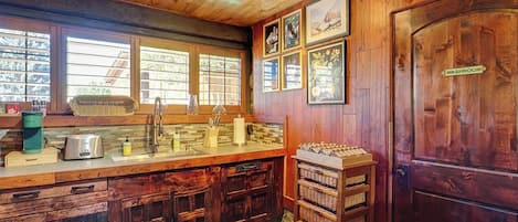 A rustic kitchen with wooden cabinets, a sink, and a coffee maker.