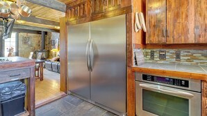 Una cocina con un refrigerador de acero inoxidable, horno y armarios de madera.