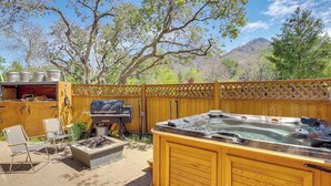 An outdoor patio with a hot tub, a grill, and a seating area. - Charming 4-bed cottage with hot tub (Sandy)