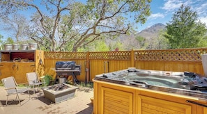 An outdoor patio with a hot tub, a grill, and a seating area.