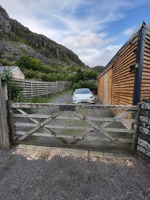 A gated driveway leading to a building with a wooden exterior.