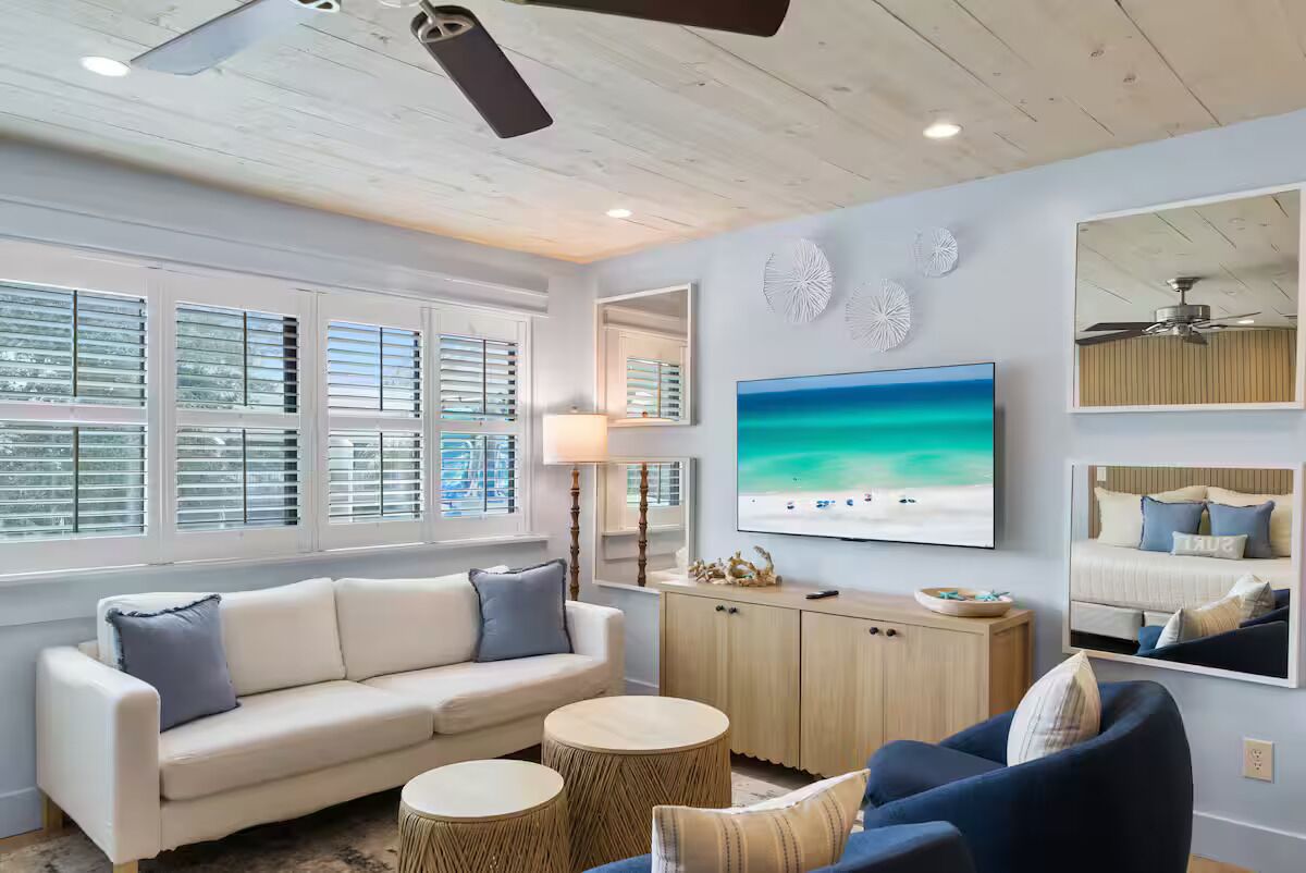A modern living room with a sofa, armchairs, a coffee table, and a TV.
