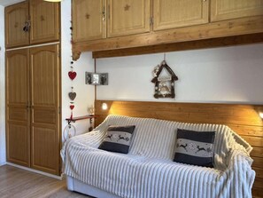 A cozy room with a wooden headboard, a sofa with patterned cushions, and a wall-mounted birdhouse. - Ski-in/ski-out & foot of the slopes, 4th floor, balcony, tv, 30m², Les Orres (Les Orres)