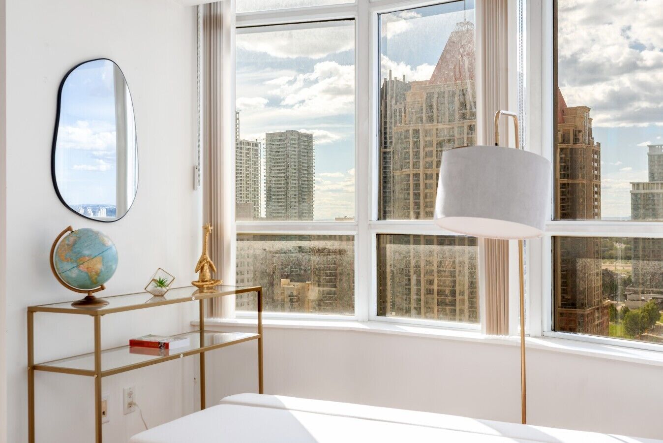 A room with a large window, a globe on a shelf, and a lamp.