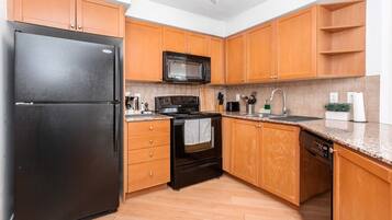 A kitchen with wooden cabinets, a black refrigerator, a microwave, a stove, and a dishwasher.