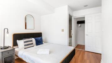 A bedroom with a bed, bedside table, lamp, and a wardrobe.
