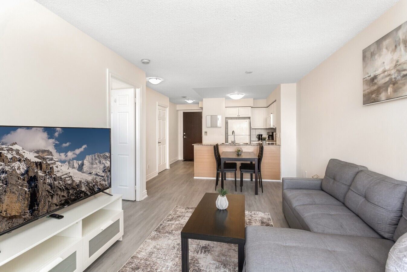 A modern living room with a flat-screen TV, a gray sofa, and a coffee table.
