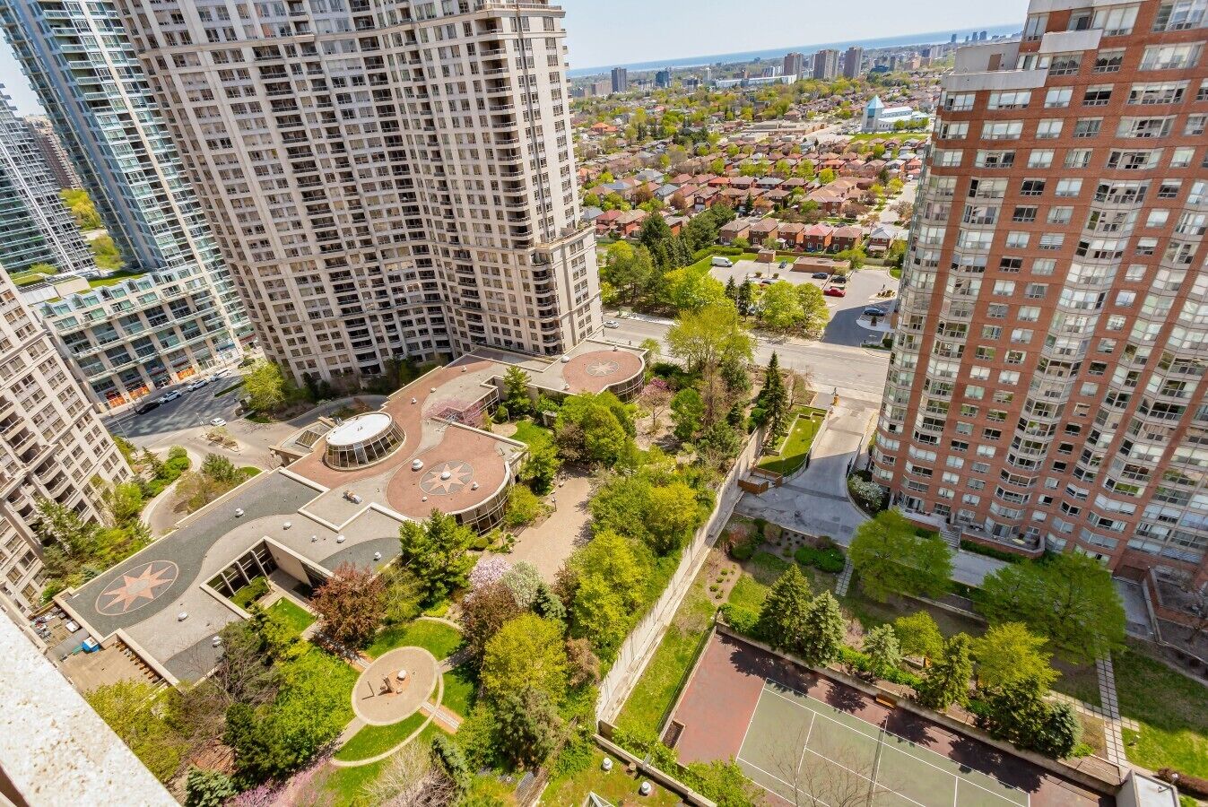 A high-rise building complex with multiple residential units, a central courtyard with a circular design, and surrounding greenery.