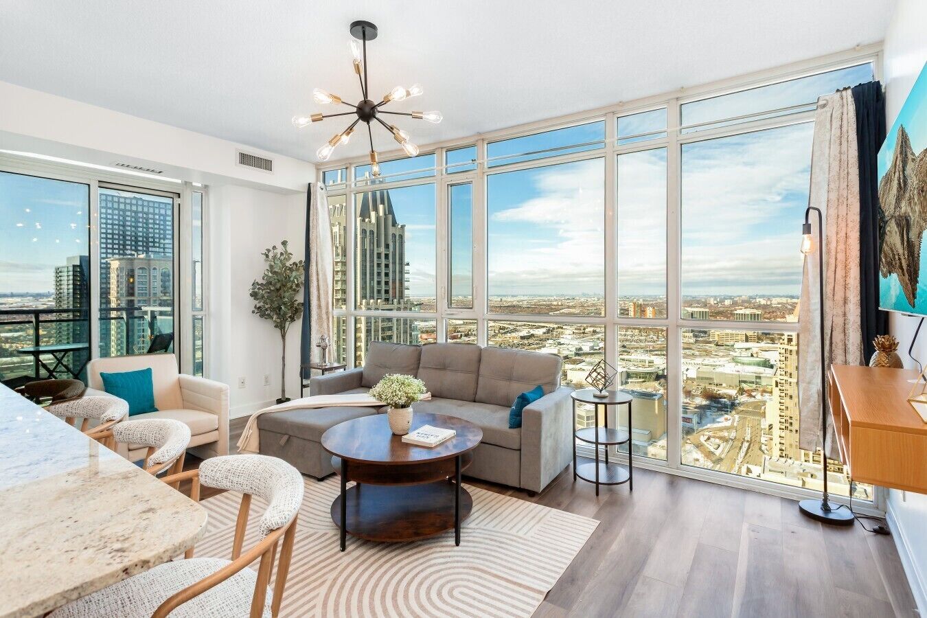 A modern living room with a large window, a round coffee table, a sofa, and a dining area.
