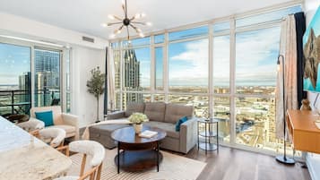A modern living room with a large window, a round coffee table, a sofa, and a dining area.